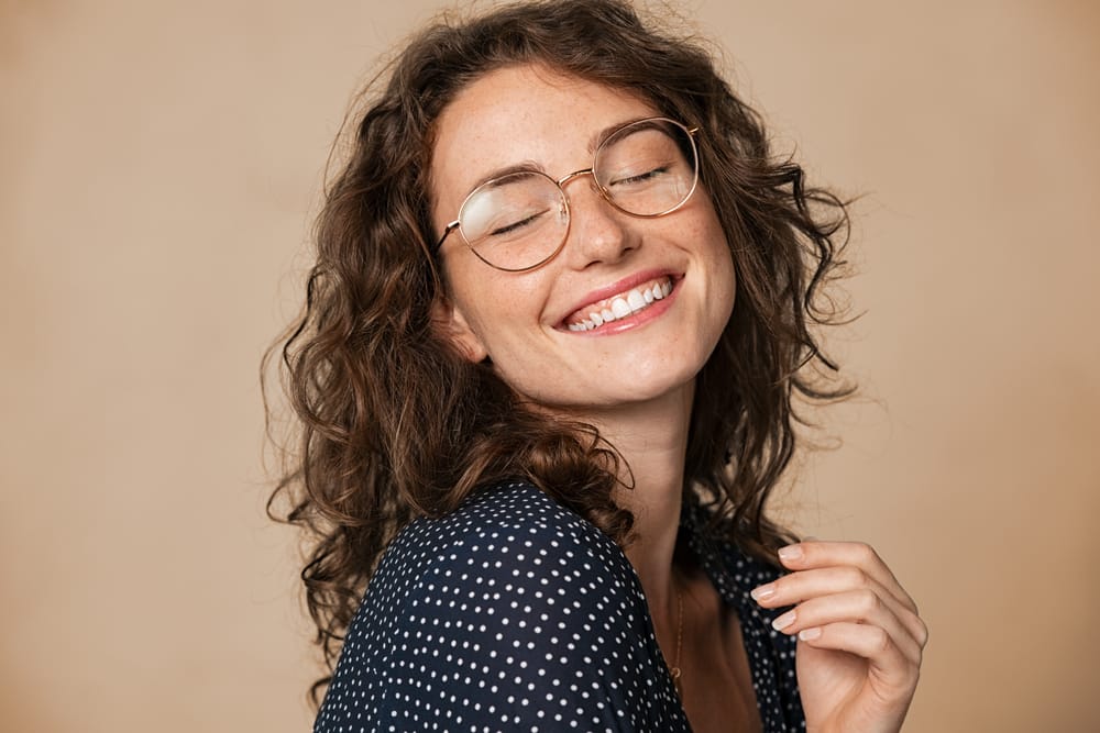 Joyful woman with smooth, glowing skin – Kirkland Laser Treatment Smiling woman with clear, radiant skin and glasses showing confidence after - Kirkland Laser Treatment